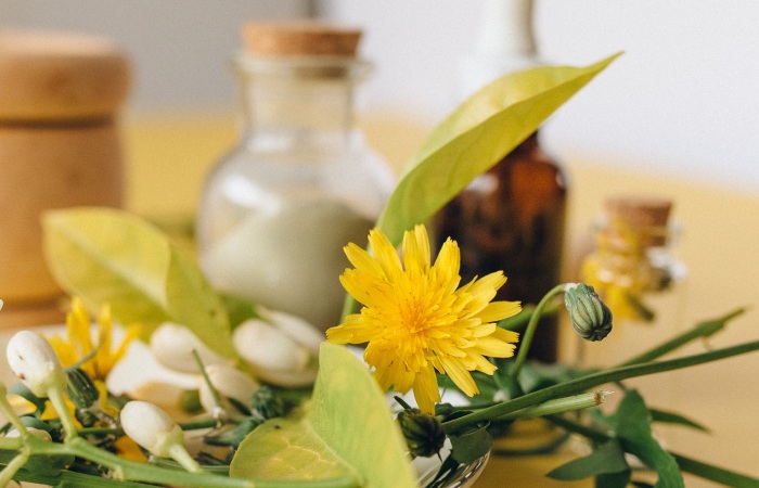 close up image of marigold, green leaves and bottles of homeopathic remedies