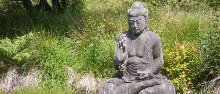 stone yoga statue in lotus position in meditation at a peaceful yoga retreat in Cornwall